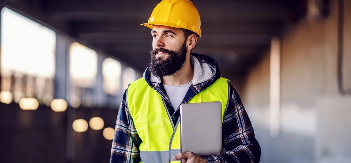 Man with a beard wearing yellow hard hat and flannel hoodie