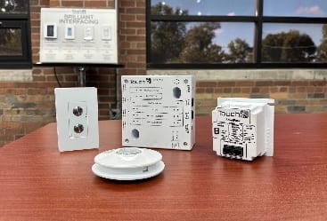 Four white lighting control products sitting on top of a brown table